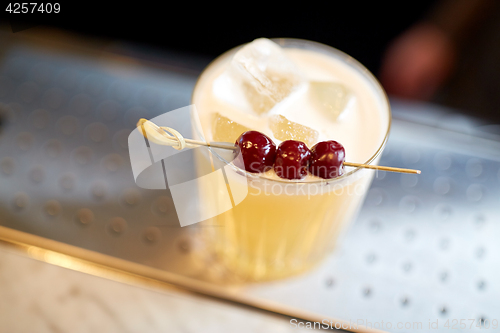 Image of glass of cocktail with cherries at bar