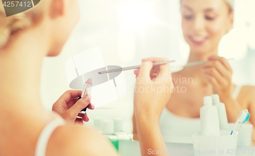 Image of woman with lipstick and make up brush at bathroom