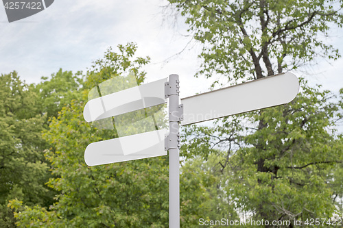 Image of tree white metal road signs in the park