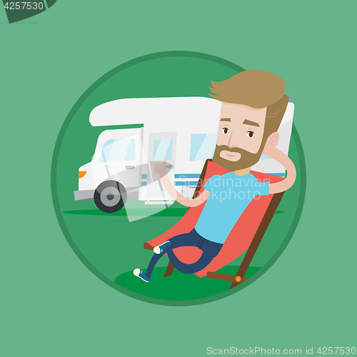 Image of Man sitting in chair in front of camper van.