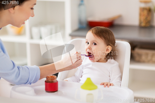 Image of happy mother feeding baby with puree at home