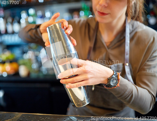 Image of close up of bartender with cocktail shaker at bar