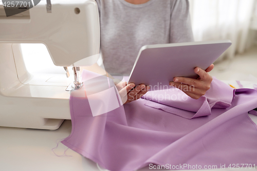 Image of tailor with sewing machine, tablet pc and fabric