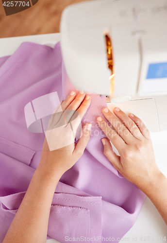 Image of tailor woman with sewing machine stitching fabric