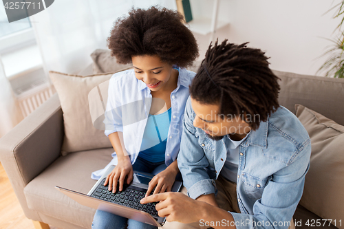 Image of smiling happy couple with laptop at home