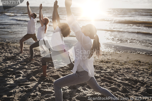 Image of group of people making yoga exercises on beach