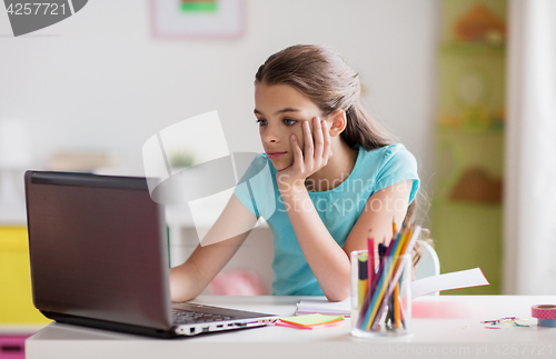 Image of bored girl with laptop and notebook at home