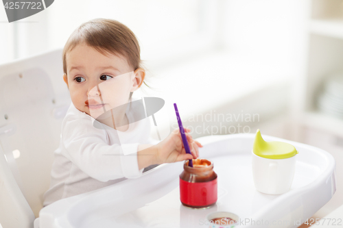 Image of baby with spoon eating puree from jar at home