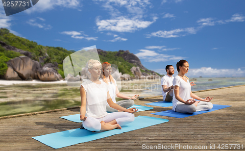 Image of people meditating in yoga lotus pose outdoors