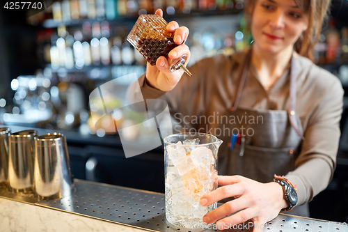 Image of woman bartender preparing cocktail at bar