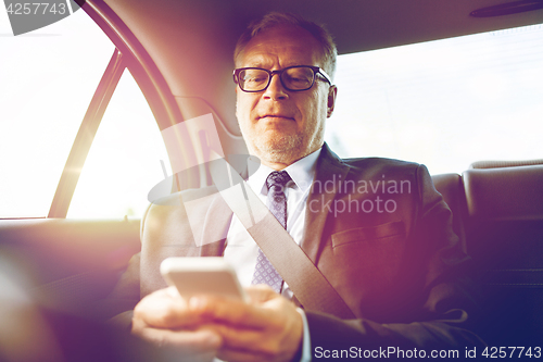 Image of senior businessman texting on smartphone in car