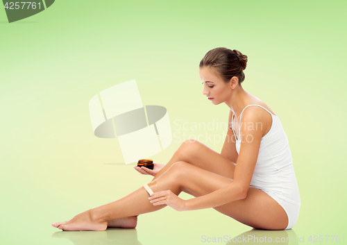 Image of beautiful woman applying depilatory wax to her leg
