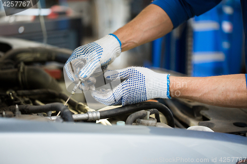 Image of mechanic with dipstick checking motor oil level