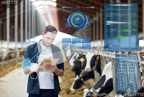 Image of farmer with clipboard and cows in cowshed on farm