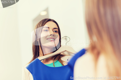 Image of happy woman with clothes at clothing store mirror