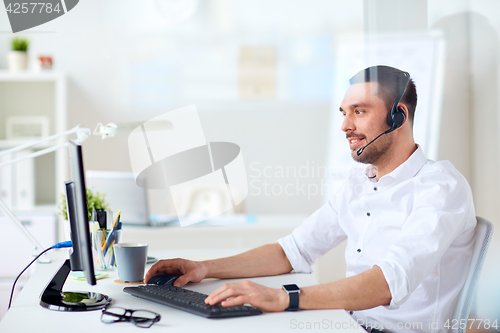 Image of businessman with headset and computer at office