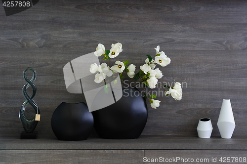 Image of decorative vases and flowers at dark wooden shelf