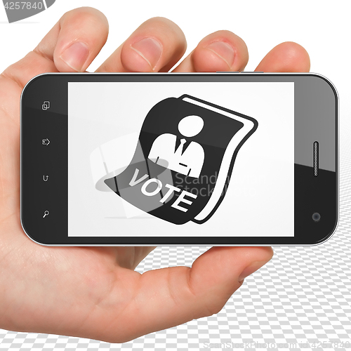 Image of Politics concept: Hand Holding Smartphone with Ballot on display