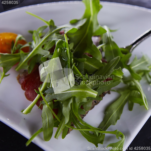 Image of slice of prosciutto or jamon with arugula leafs