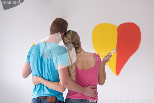 Image of couple are painting a heart on the wall