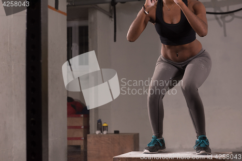 Image of black woman is performing box jumps at gym