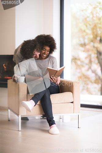 Image of multiethnic couple hugging in front of fireplace