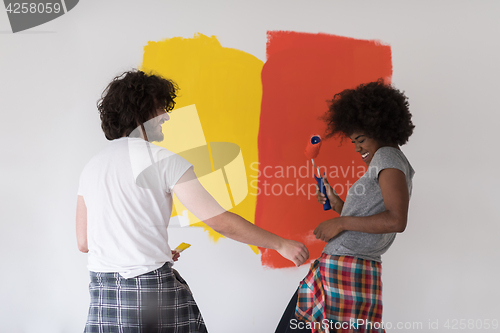 Image of multiethnic couple painting interior wall