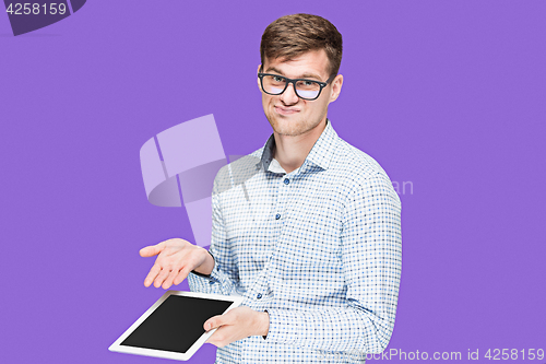 Image of The young man in a shirt working on laptop on lilac backgroundin