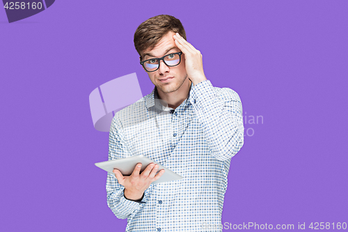 Image of The young man in a shirt working on laptop on lilac backgroundin