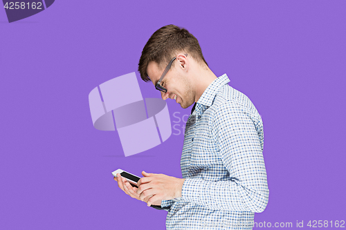 Image of The young man in a shirt working on laptop on lilac backgroundin