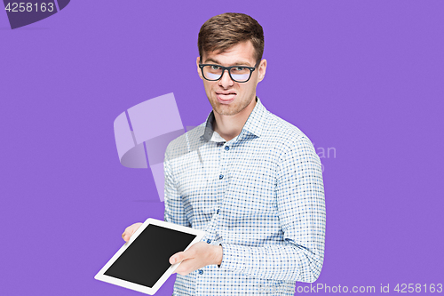 Image of The young man in a shirt working on laptop on lilac backgroundin