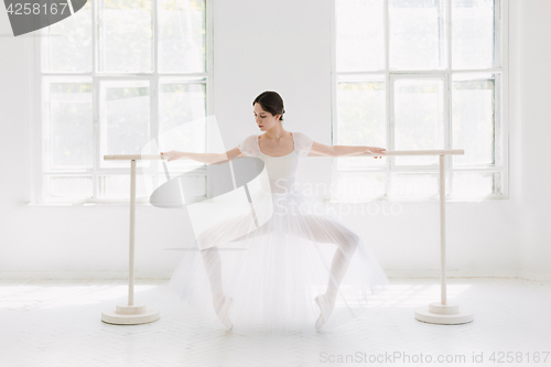 Image of Young and incredibly beautiful ballerina is posing and dancing in a white studio