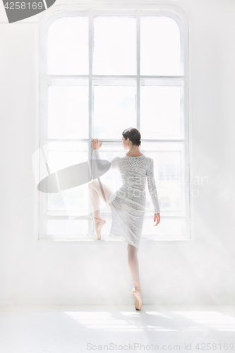 Image of Young and incredibly beautiful ballerina is posing and dancing in a white studio