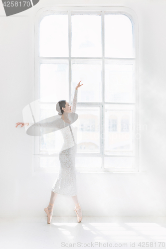 Image of Young and incredibly beautiful ballerina is posing and dancing in a white studio