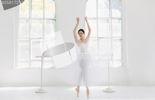 Image of Young and incredibly beautiful ballerina is posing and dancing in a white studio