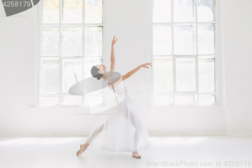 Image of Young and incredibly beautiful ballerina is posing and dancing in a white studio