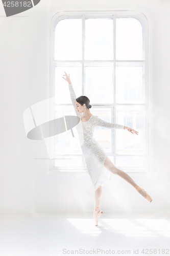 Image of Young and incredibly beautiful ballerina is posing and dancing in a white studio