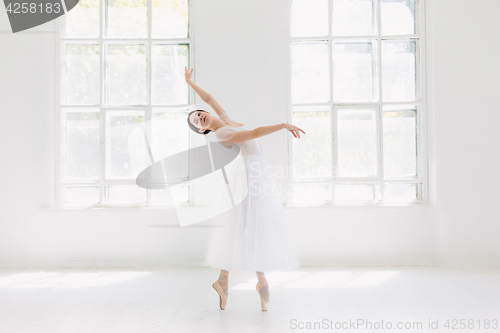 Image of Young and incredibly beautiful ballerina is posing and dancing in a white studio