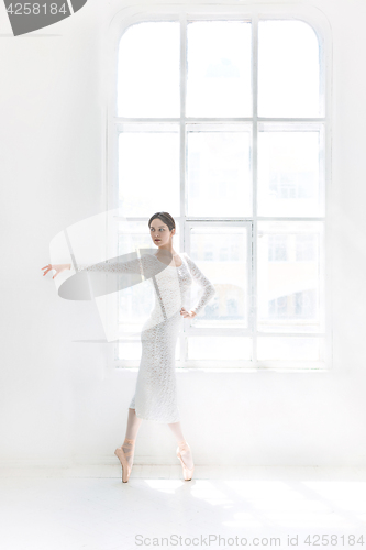 Image of Young and incredibly beautiful ballerina is posing and dancing in a white studio