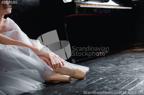 Image of Young ballerina dancing, closeup on legs and shoes, sitting in pointe shooses