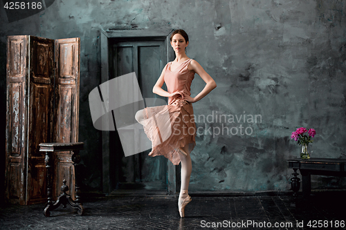 Image of Young and incredibly beautiful ballerina is posing and dancing in a black studio