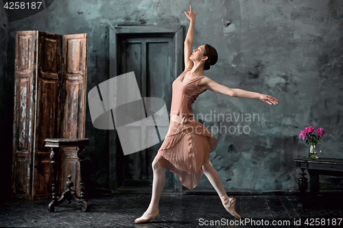 Image of Young and incredibly beautiful ballerina is posing and dancing in a black studio