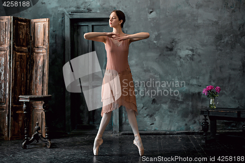 Image of Young and incredibly beautiful ballerina is posing and dancing in a black studio