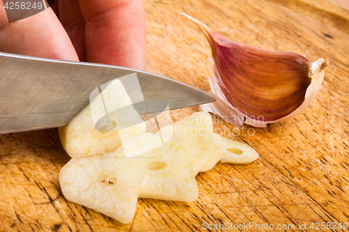 Image of hand slicing garlic cloves