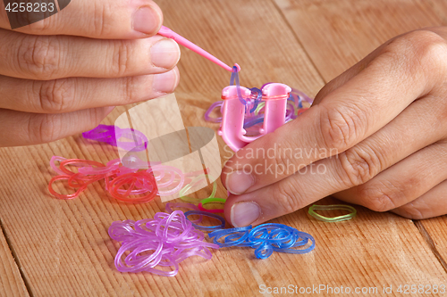 Image of hands making rubber band bracelet, closeup