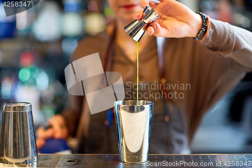 Image of bartender with cocktail shaker and jigger at bar