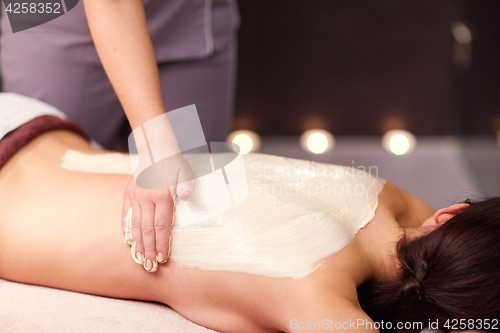 Image of woman having back massage with cream at spa
