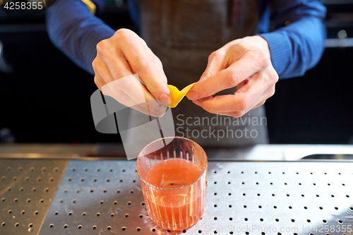 Image of bartender with glass of cocktail and lemon peel