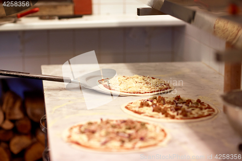 Image of peel taking pizza off table at pizzeria