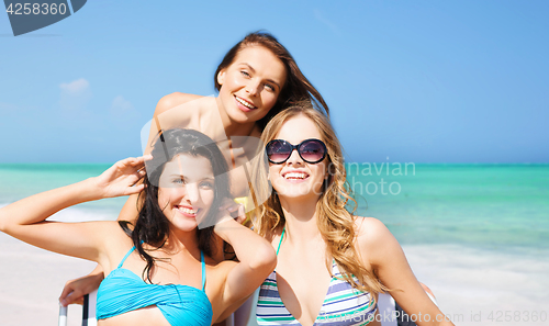 Image of happy women sunbathing on chairs over summer beach